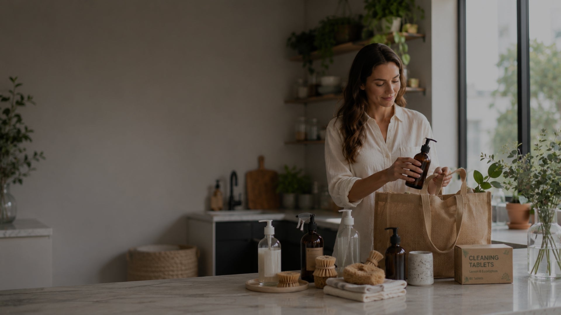 Woman in a kitchen preparing a bottle of soap with various products on the counter.